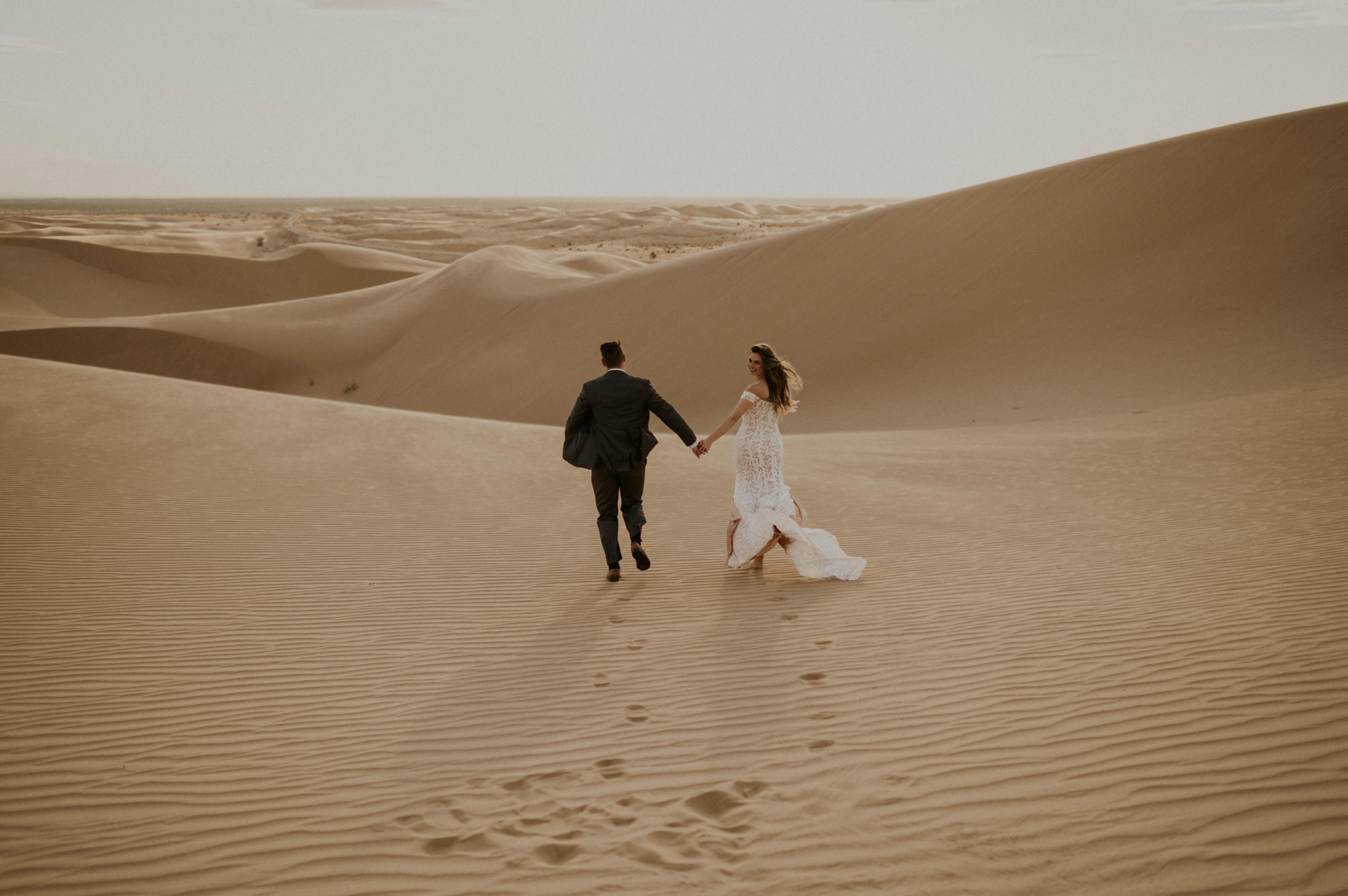 wedding couple running through sand dunes