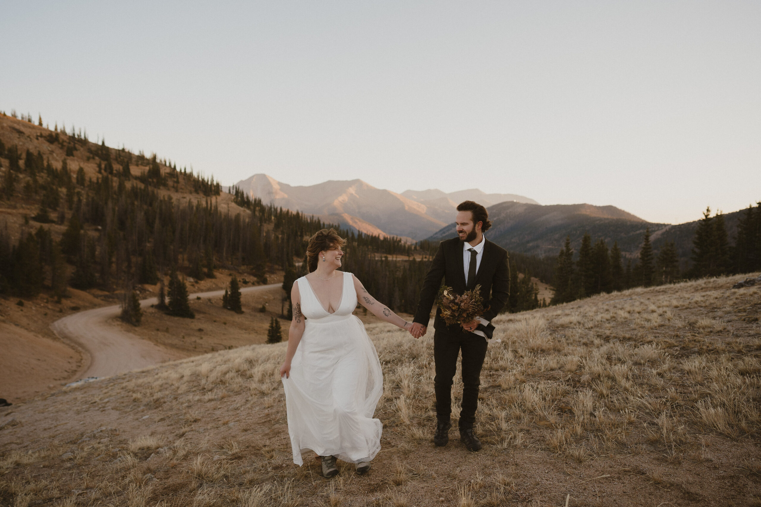 wedding couple running on mountain in colorado during sunrise