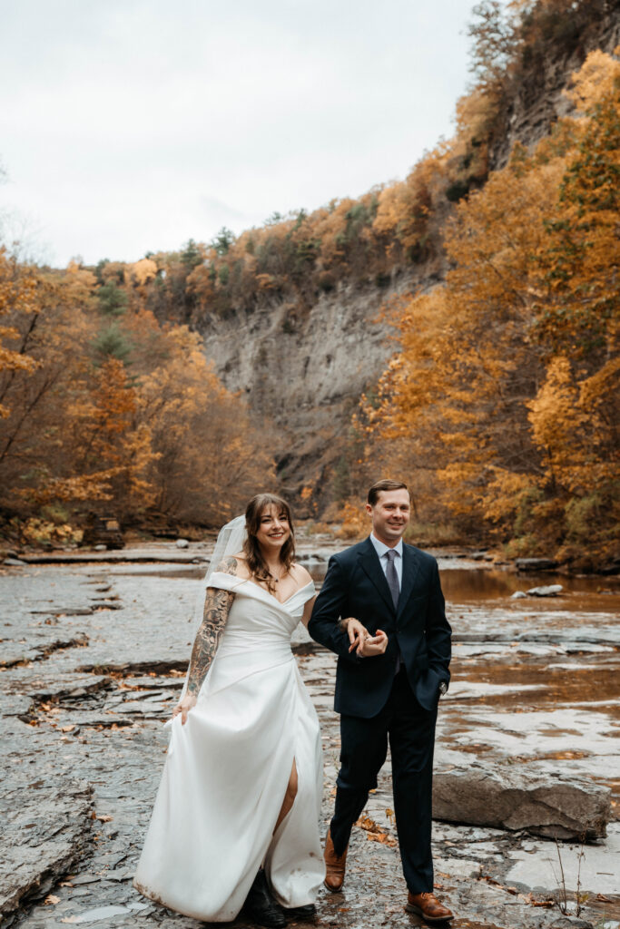 wedding couple walking through fall foliage in upstate new york